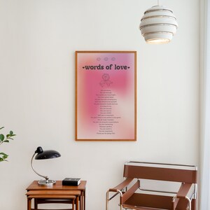 Pode incluir: Uma impress&atilde;o emoldurada com um fundo degrad&ecirc; rosa e roxo. A impress&atilde;o apresenta o texto "words of love" e uma pequena ilustra&ccedil;&atilde;o de um cora&ccedil;&atilde;o com uma flor dentro. A impress&atilde;o est&aacute; pendurada em uma parede branca em um quarto com uma cadeira marrom e uma pequena planta.