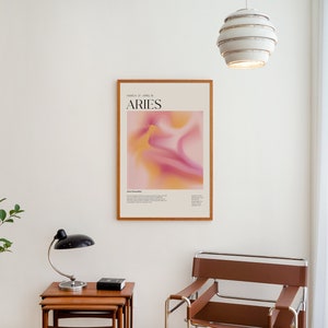 May include: A framed poster with a pink and yellow abstract design and the text "Aries March 21 - April 19" in black.