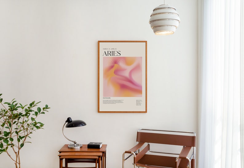May include: A framed poster with a pink and yellow abstract design and the text "Aries March 21 - April 19" in black.