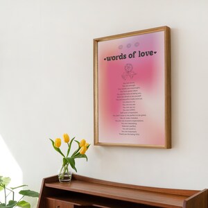 Pode incluir: Uma impress&atilde;o emoldurada com um fundo degrad&ecirc; rosa e roxo. A impress&atilde;o apresenta uma ilustra&ccedil;&atilde;o em preto e branco de uma rosa e o texto "words of love" em preto. A impress&atilde;o est&aacute; pendurada em uma parede branca.