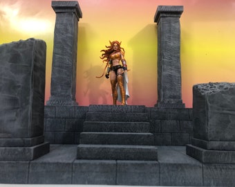 May include: A female action figure with long red hair stands on a grey stone platform with two pillars. The platform has steps leading up to it. The background is a gradient of orange and yellow.