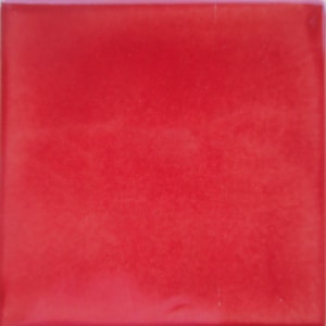 May include: A solid red square tile with a glossy finish. The tile has a smooth surface and a vibrant, saturated color. The edges of the tile are slightly rounded.