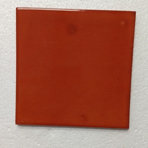 May include: A solid orange ceramic tile with a smooth, glossy finish.
