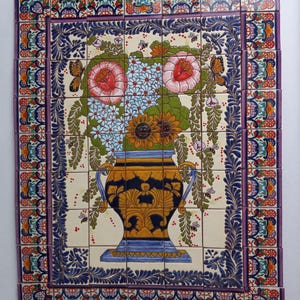 May include: A colorful ceramic tile mural depicting a vase filled with flowers. The vase is decorated with blue, gold, and black designs. The flowers are pink, white, and yellow. The background is a cream color with a blue and white border.