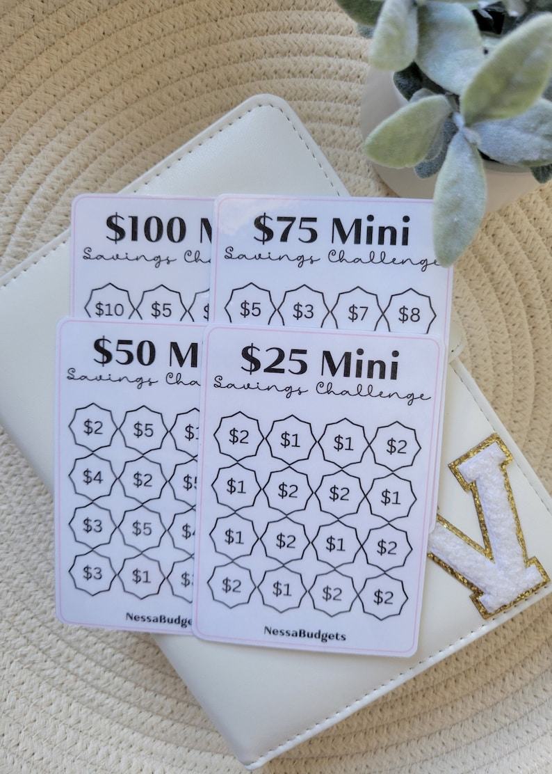 May include: Four printable savings challenge cards with different dollar amounts. The cards are white with black text and lines. The cards are labeled "$100 Savings Challenge", "$75 Mini Savings Challenge", "$50 Mini Savings Challenge", and "$25 Mini Savings Challenge".