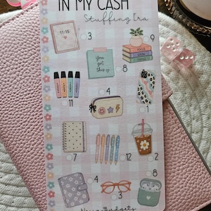 Peut inclure: Une planche d'autocollants avec diverses illustrations et du texte, dont la phrase "IN MY CASH Stuffing Era" et "You got this ♡". La planche présente des images d'une coque de téléphone, de stylos, d'un carnet, de lunettes et d'une boisson au café. Le texte "Nessa Budgets" est également visible.