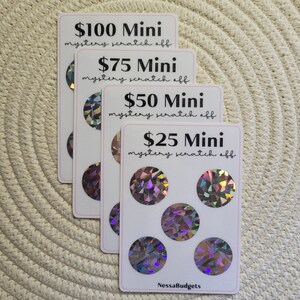 May include: Four white cards with holographic scratch-off circles. The cards are stacked on top of each other. The top card has the text "$100 Mini mystery scratch off". The second card has the text "$75 Mini mystery scratch off". The third card has the text "$50 Mini mystery scratch off". The bottom card has the text "$25 Mini mystery scratch off" and the text "NessaBudgets".