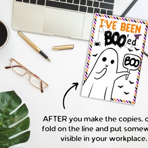 May include: A rectangular Halloween greeting card featuring the text I'VE BEEN BOO'ed in orange and black. The illustration shows a white ghost holding a sign that says BOO, surrounded by small black spiders, bats, and a purple witch hat.