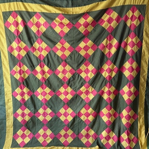 Puede incluir: Un edredón hecho a mano con un patrón de diamantes repetido. El edredón presenta un fondo verde oscuro con formas de diamantes rosas y amarillas alternas. Un borde amarillo enmarca el edredón, agregando un toque de color al diseño.