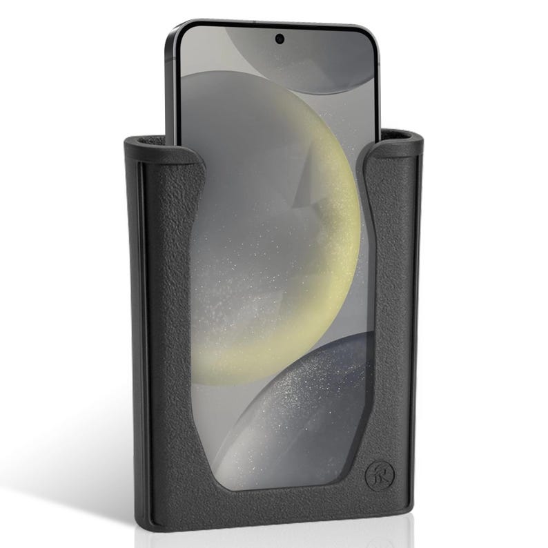 K&ouml;nnte beinhalten: Ein schwarzer Telefonhalter mit strukturierter Oberfl&auml;che, der ein Smartphone h&auml;lt. Der Bildschirm des Telefons zeigt ein verschwommenes, abstraktes Design mit Gelb- und Graut&ouml;nen. Der Halter hat einen abgerundeten Boden und ein Logo.