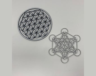 May include: Two white wooden wall decor pieces with geometric designs. The first piece is a circle with a flower of life pattern. The second piece is a hexagon with a geometric pattern inside.