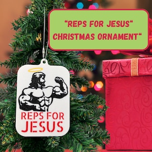 May include: White Christmas ornament with a black and white image of a muscular Jesus with a halo. The ornament says "Reps for Jesus" in red letters.