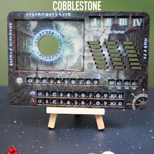 May include: A rectangular game board with the word "COBBLESTONE" at the top. The board features a circular cutout, numbers, and various game-related elements. It is supported by a small wooden easel.