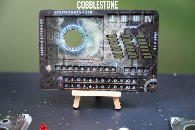 May include: A rectangular game board with the word "COBBLESTONE" at the top. The board features a circular cutout, numbers, and various game-related elements. It is supported by a small wooden easel.