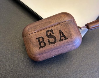 May include: A dark brown wooden case with the initials "BSA" engraved on the top. The case is closed and has a leather strap attached.