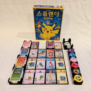Może przedstawiać: Koreańska wersja językowa gry planszowej "Pokemon: Gra Karciana Kolekcjonerska" z ilustracją Pikachu na pudełku. Gra zawiera planszę do gry, karty i żetony.