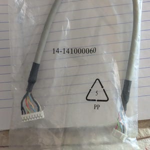 May include: A gray cable with multiple colored wires and white connectors at each end, packaged in a clear plastic bag. The bag has the number "14-141000060" printed on it, along with a recycling symbol.
