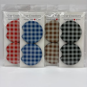 May include: Four sets of car coasters in clear plastic packaging. Each set features two coasters with a gingham pattern in red, blue, brown, and black. The packaging reads "Car Coasters" and "Handmade with love."