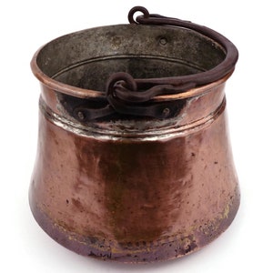 May include: A vintage copper pot with a worn handle. The pot has a rounded bottom and a wide opening. The copper has a patina of age and use.