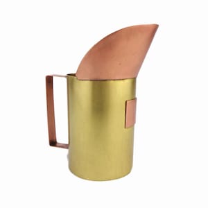 Op de afbeelding: Een gouden kan met een koperen tuit en handvat. De kan heeft een gehamerde afwerking en een koperen accent aan de zijkant.