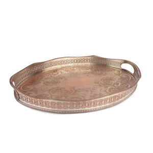 Pode incluir: Uma bandeja de servir oval de prata com um design ornamentado e duas alças. A bandeja tem uma borda elevada e uma superfície lisa.