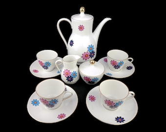 May include: A white tea set with a floral design. The set includes a teapot, creamer, sugar bowl, and four cups and saucers.