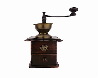 May include: A vintage wooden coffee grinder with a brass hopper and a hand crank. The grinder has a drawer for storing coffee beans and a brass plaque with a design of two people.