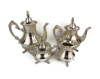 May include: A silver tea set with a teapot, creamer, and sugar bowl. The set has an ornate design with a polished finish.