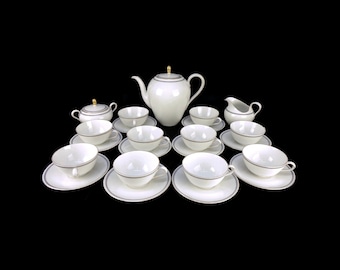 May include: A white porcelain tea set with gold accents. The set includes a teapot, creamer, sugar bowl, and 10 cups and saucers.