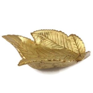 May include: A gold leaf-shaped dish, perfect for holding small items like jewelry or trinkets.