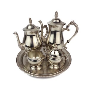 May include: A silver tea set with a teapot, creamer, sugar bowl, and tray. The set is decorated with ornate details and has a polished finish.