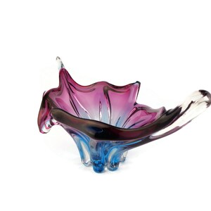 Peut inclure: Un bol en verre de couleur violet et bleu avec un design ondul&eacute; et organique. Le bol est en verre transparent avec une finition iris&eacute;e violette et bleue.