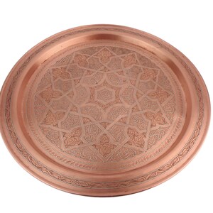 May include: A round copper serving tray with an intricate geometric design etched into the surface.