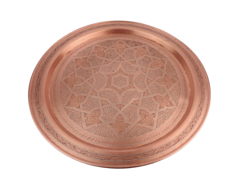 May include: A round copper serving tray with an intricate geometric design etched into the surface.