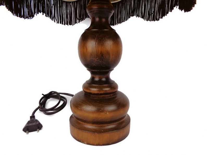 May include: A wooden table lamp base with a dark brown finish. The base has a round, bulbous shape with a smaller, round top. The lamp base has a cord with a two-prong plug.
