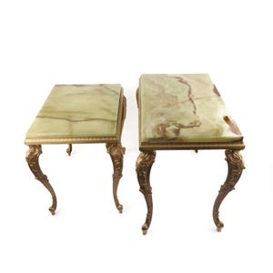 May include: Two antique side tables with rectangular green marble tops and ornate gold-colored legs. The tables have a classic, elegant design, perfect for a living room or bedroom. Each table is approximately 24 inches long, 18 inches wide, and 20 inches tall.