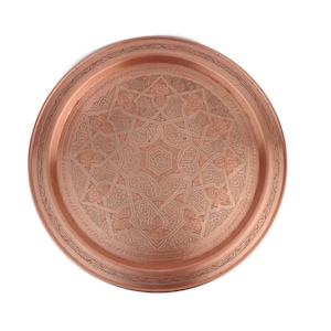 May include: A round copper serving tray with an intricate geometric design. The tray has a raised rim and a polished finish.