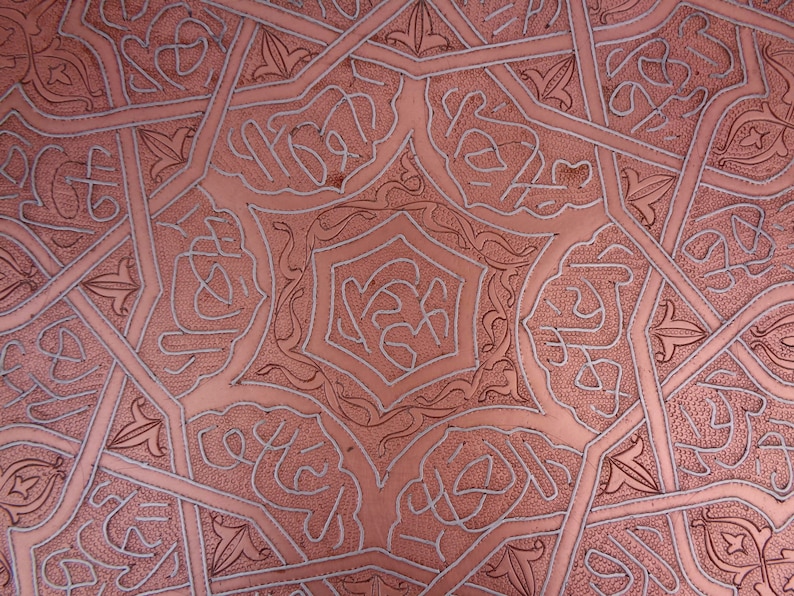May include: A copper tray with an intricate geometric pattern etched into the surface. The pattern is in a silver color and creates a beautiful contrast against the copper.