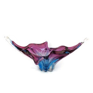 Peut inclure: Un bol en verre avec un design abstrait unique. Le bol est en verre transparent avec des tourbillons de violet et de bleu.