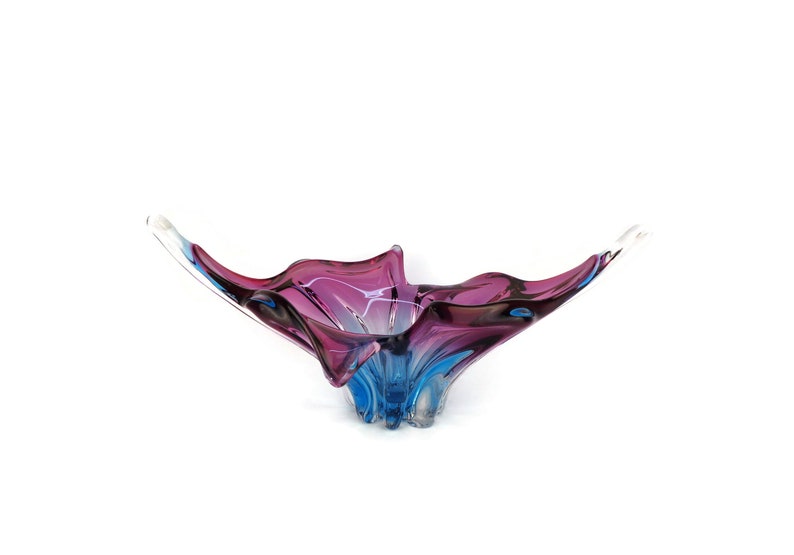 Peut inclure: Un bol en verre avec un design abstrait unique. Le bol est en verre transparent avec des tourbillons de violet et de bleu.