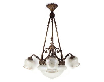 May include: A vintage brass chandelier with five frosted glass shades. The chandelier has a decorative, ornate design with twisted rope accents.