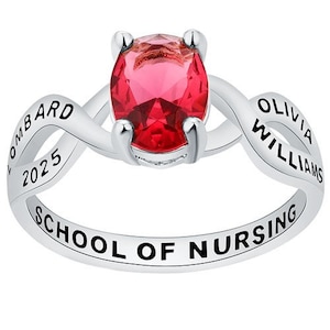 May include: A silver ring with a red gemstone and the inscription "Olivia Williams School of Nursing 2025" on the band.
