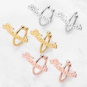 May include: Six gold, silver, and rose gold ear cuffs with the name "Hannah" written on them. The ear cuffs are designed to wrap around the ear.