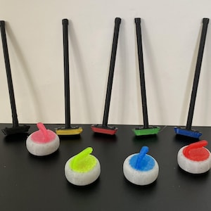 May include: A set of five curling brooms with black handles and colored heads. The heads are red, yellow, green, blue, and black. There are also five curling stones with white bases and colored handles. The handles are pink, green, blue, red, and black.