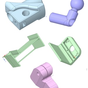 Op de afbeelding: Vijf 3D-geprinte modellen in verschillende kleuren en vormen. Een lichtblauw model met een gebogen handvat, een paars model met een bal bovenop, een groen model met een rechthoekige basis, een groen model met een rechthoekige basis en een gebogen zijde, en een roze model in de vorm van een hart.