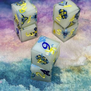May include: Three sets of white dice with blue and yellow floral designs. The dice are stacked on top of each other. The numbers on the dice are 1, 2, 3, 4, 5, 6, 7, 8, and 9.