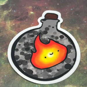 Puede incluir: Una pegatina redonda con una botella gris con un tap&oacute;n de corcho y una llama naranja sonriente en su interior. La botella tiene un patr&oacute;n gris y negro moteado.