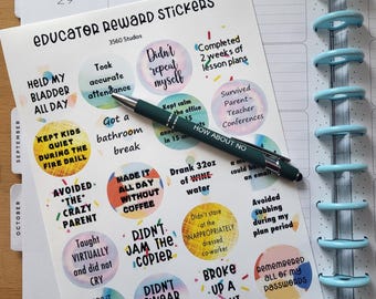 May include: A sheet of "Educator Reward Stickers" with colorful circular designs and humorous phrases, such as "Held my bladder all day." A green pen rests on the stickers, next to a planner with blue rings.