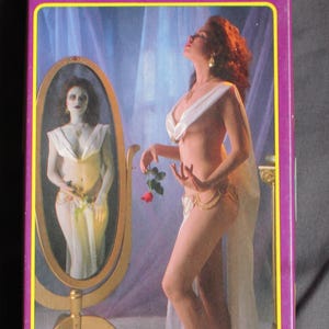 May include: A purple box with a yellow border features the text "GRENADIER MODELS fantastic females of an ancient world." The box art depicts a woman in a white garment holding a red rose, with a mirror reflection. The text "PRINCESS ACHMIRI" is also visible.