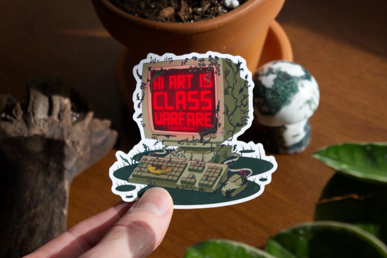 May include: A sticker featuring a vintage computer with the text "AI ART IS CLASS WARFARE" in red. The computer is overgrown with vines and sits on a green base. A mouse and keyboard are also visible.